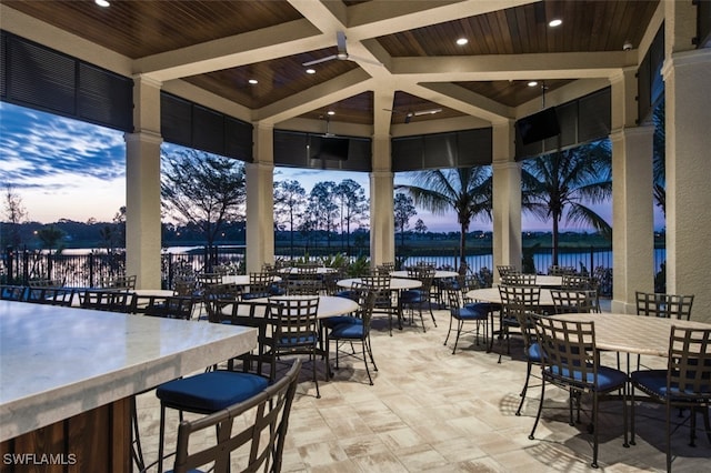 patio terrace at dusk with a water view and an outdoor bar