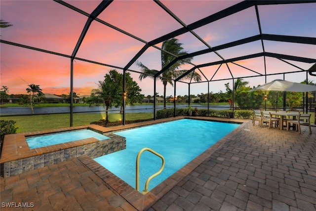 pool at dusk featuring a patio, an in ground hot tub, a water view, and a lanai