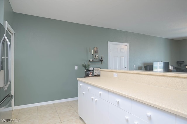 kitchen featuring stainless steel fridge, white cabinets, and light tile patterned floors