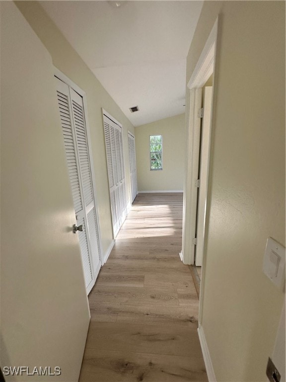 hallway featuring light hardwood / wood-style floors and lofted ceiling