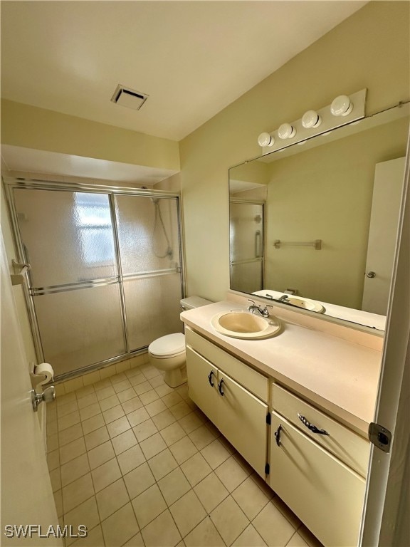 bathroom featuring vanity, toilet, tile patterned floors, and an enclosed shower