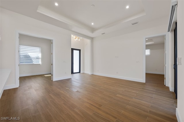 spare room featuring a raised ceiling and a chandelier