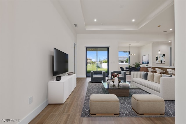 living room featuring a raised ceiling and a chandelier