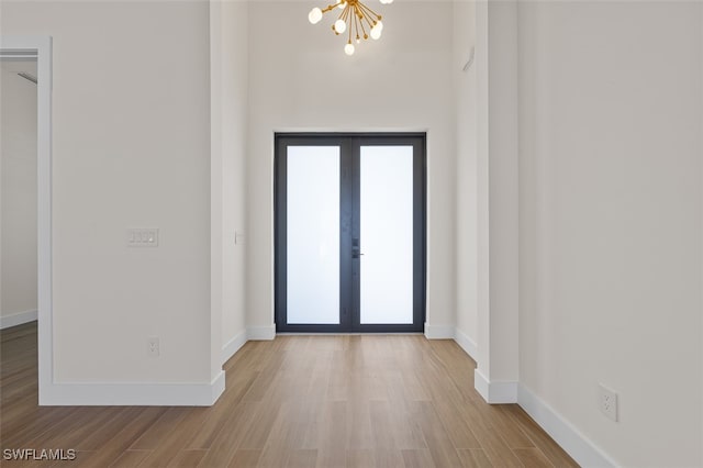 entrance foyer featuring french doors, light hardwood / wood-style flooring, and an inviting chandelier