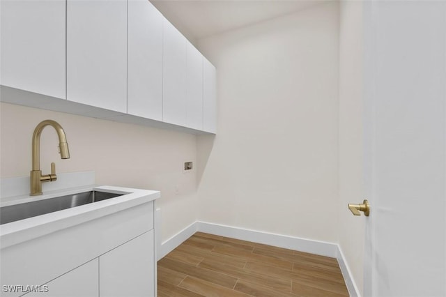 209 Kismet Pkwy E, Cape Coral, FL 33909 - laundry room featuring cabinet space, washer hookup, a sink, light wood finished floors, and baseboards
