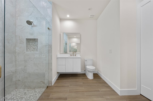 bathroom with vanity, toilet, and tiled shower