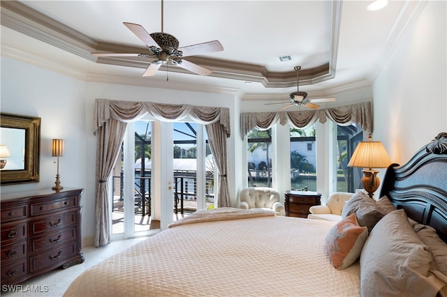 carpeted bedroom with ceiling fan, access to outside, a tray ceiling, ornamental molding, and a water view