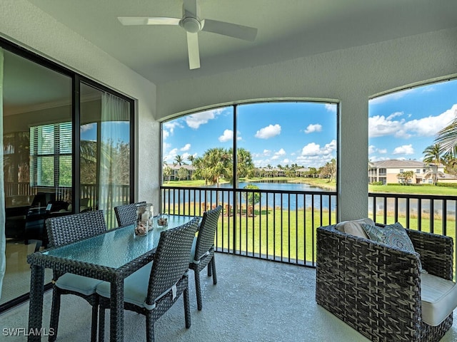 sunroom featuring ceiling fan and a water view