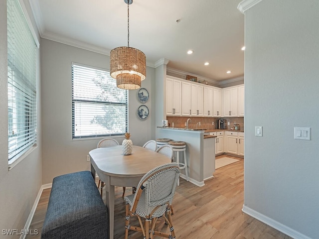 dining space with light hardwood / wood-style flooring, crown molding, and sink