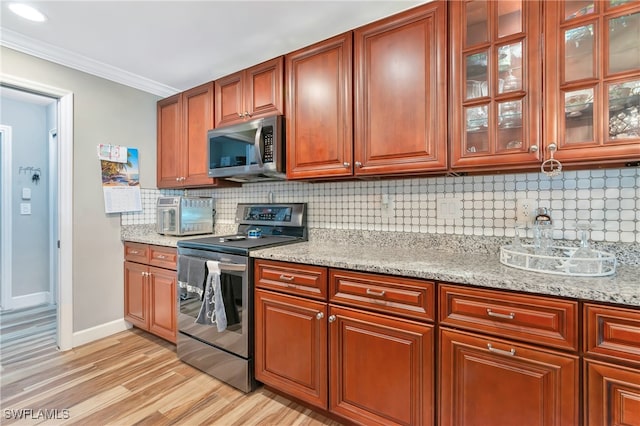 kitchen featuring light stone countertops, decorative backsplash, appliances with stainless steel finishes, and crown molding