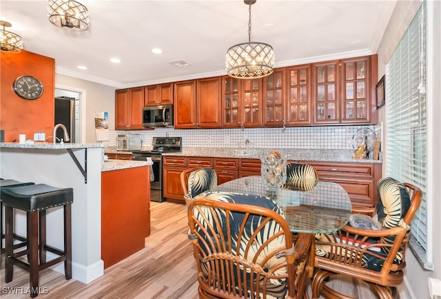 kitchen with tasteful backsplash, appliances with stainless steel finishes, a chandelier, and pendant lighting