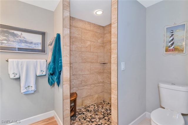 bathroom with toilet, tiled shower, and hardwood / wood-style floors