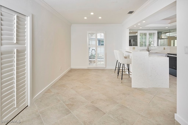 kitchen with crown molding, stainless steel range with electric stovetop, a breakfast bar area, and plenty of natural light