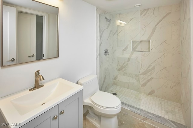 bathroom featuring vanity, toilet, tile patterned floors, and tiled shower