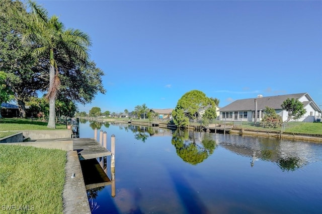 view of dock with a water view and a lawn