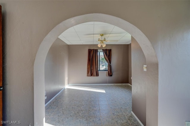 empty room with ceiling fan, tile patterned floors, and a drop ceiling