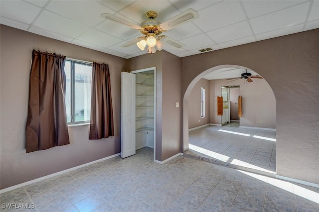 unfurnished bedroom with light tile patterned flooring, a paneled ceiling, a closet, and ceiling fan