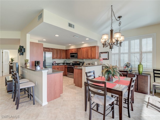 kitchen with kitchen peninsula, stainless steel appliances, light tile patterned flooring, pendant lighting, and a chandelier