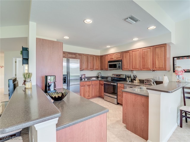 kitchen featuring sink, a breakfast bar, kitchen peninsula, stainless steel appliances, and light tile patterned floors