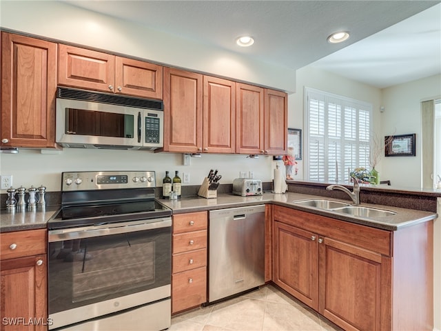 kitchen with light tile patterned floors, appliances with stainless steel finishes, sink, and kitchen peninsula