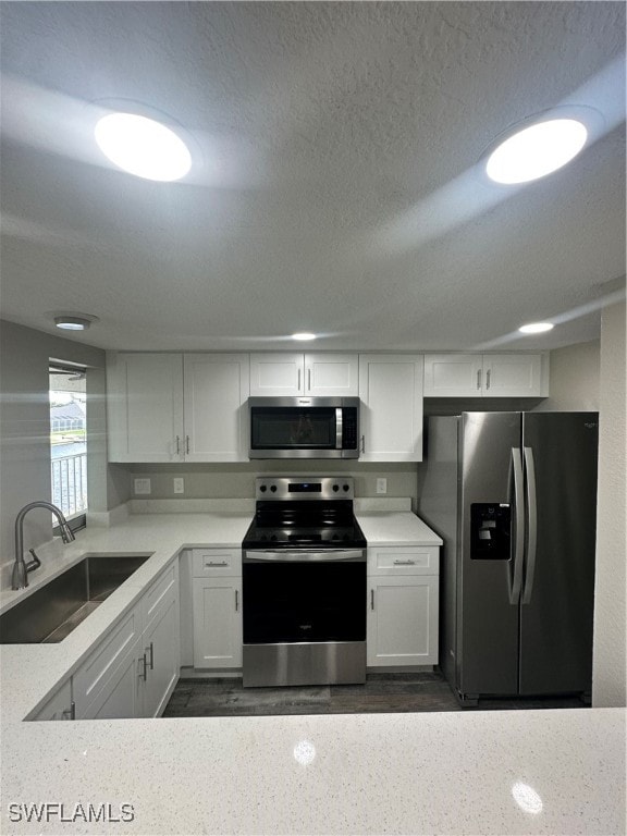 kitchen featuring appliances with stainless steel finishes, white cabinets, sink, and a textured ceiling