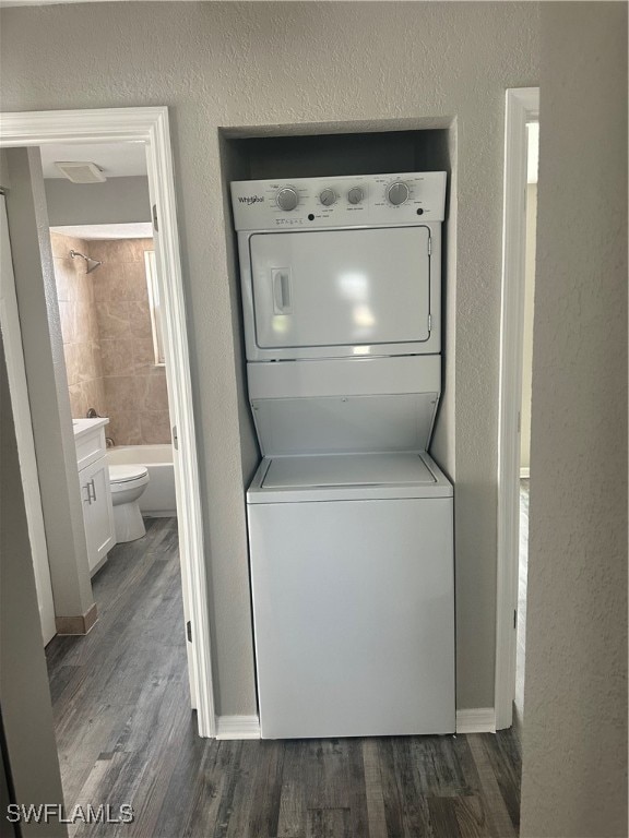 washroom with dark wood-type flooring and stacked washer and dryer