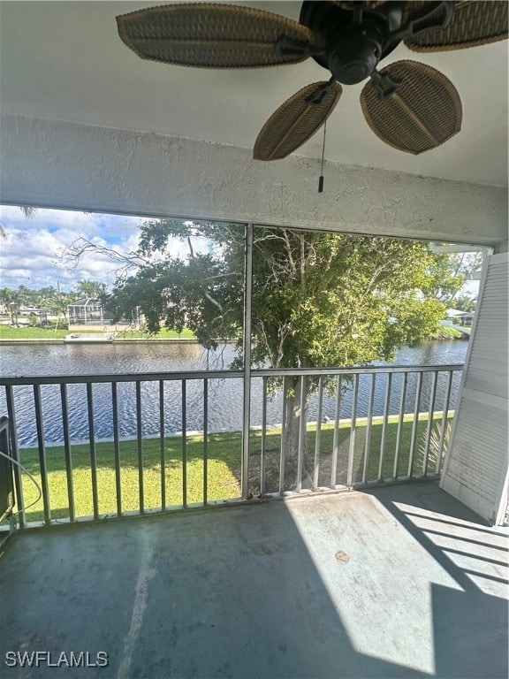 unfurnished sunroom featuring a water view and ceiling fan