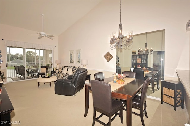 dining space with ceiling fan with notable chandelier, light colored carpet, and high vaulted ceiling