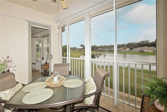 sunroom / solarium with ceiling fan and a water view