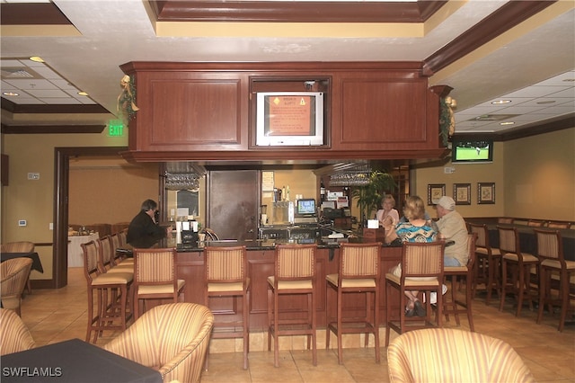 bar with a raised ceiling, ornamental molding, and light tile patterned flooring