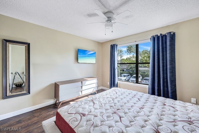 bedroom with ceiling fan, wood finished floors, baseboards, and a textured ceiling