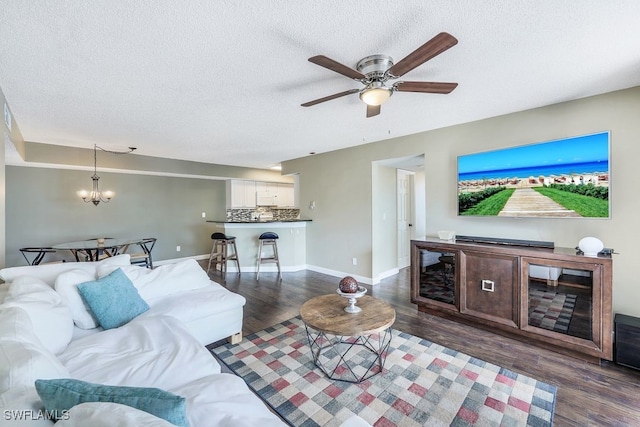 living area with baseboards, a textured ceiling, and wood finished floors