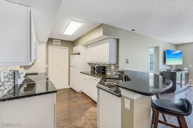 kitchen featuring white cabinets, dark hardwood / wood-style flooring, a textured ceiling, sink, and white appliances