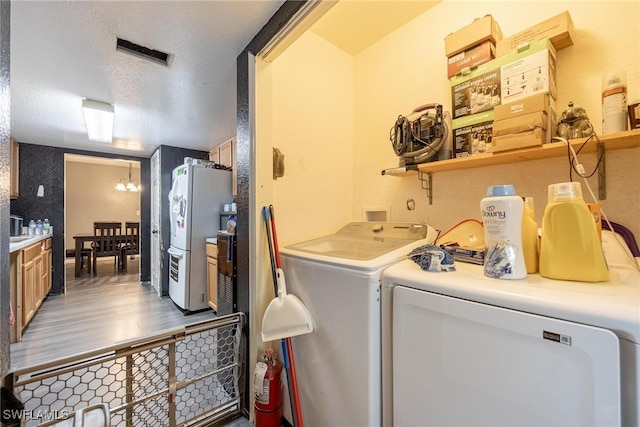 laundry area with an inviting chandelier, hardwood / wood-style floors, a textured ceiling, and washing machine and dryer