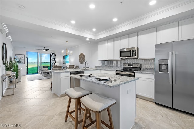 kitchen featuring a breakfast bar area, kitchen peninsula, a center island, light stone countertops, and appliances with stainless steel finishes