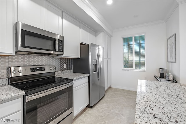 kitchen featuring white cabinets, tasteful backsplash, appliances with stainless steel finishes, light stone countertops, and crown molding