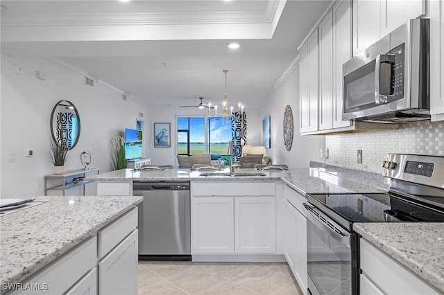 kitchen with white cabinetry, stainless steel appliances, light stone countertops, and an inviting chandelier