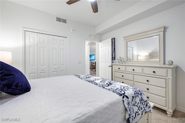 bedroom featuring light colored carpet, a closet, and ceiling fan