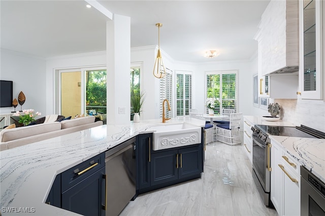 kitchen with custom range hood, white cabinets, decorative light fixtures, appliances with stainless steel finishes, and tasteful backsplash