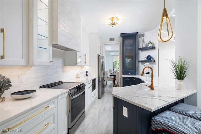 kitchen with light stone counters, appliances with stainless steel finishes, hanging light fixtures, and white cabinets