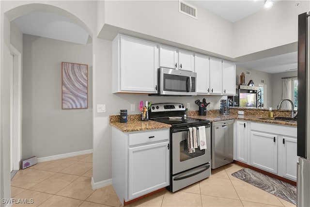 kitchen with stainless steel appliances, dark stone countertops, and white cabinets