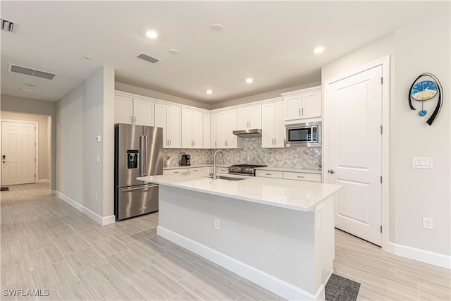 kitchen featuring sink, appliances with stainless steel finishes, a kitchen island with sink, and white cabinets