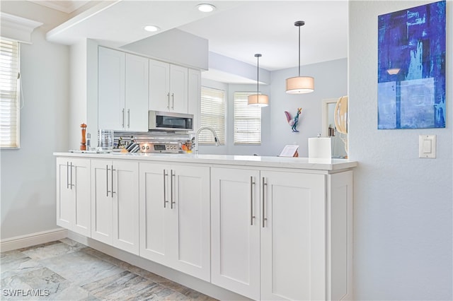 kitchen featuring stainless steel appliances, sink, pendant lighting, and white cabinets