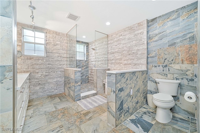 bathroom featuring vanity, tile walls, toilet, and tiled shower