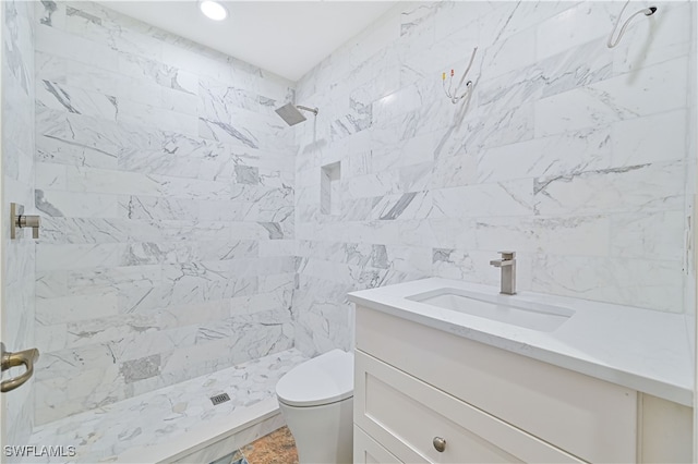 bathroom featuring vanity, toilet, and a tile shower