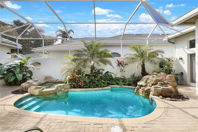 view of pool with glass enclosure and a patio area