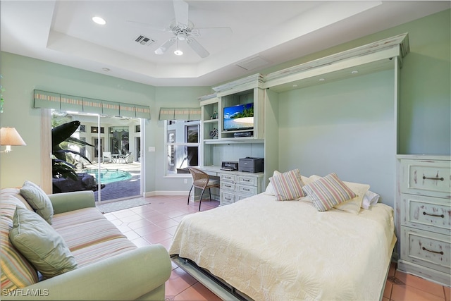 bedroom with ceiling fan, access to exterior, multiple windows, and a raised ceiling