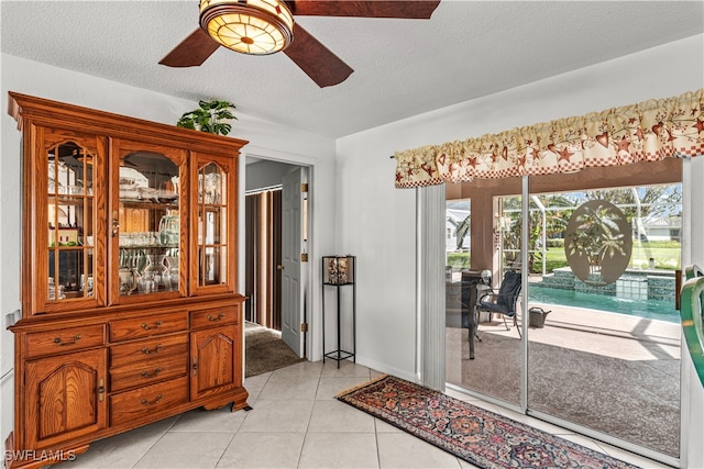 interior space featuring a textured ceiling, light tile patterned flooring, and ceiling fan