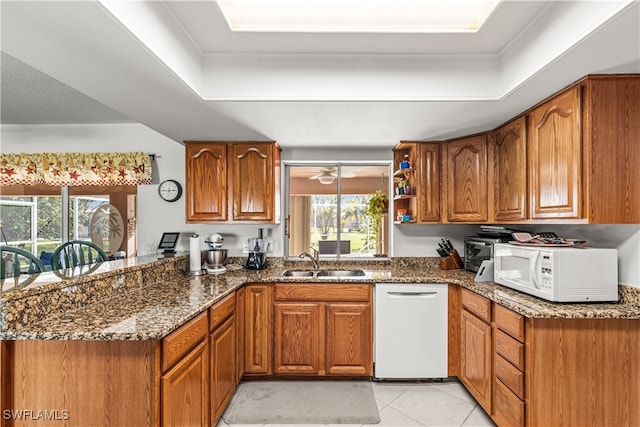 kitchen featuring dark stone countertops, a healthy amount of sunlight, sink, and white appliances