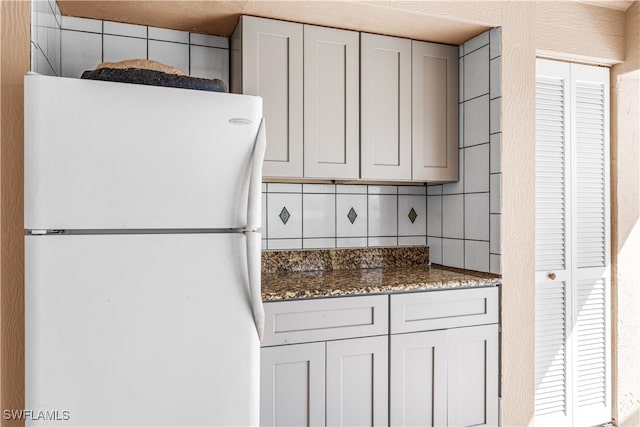 kitchen with dark stone countertops, backsplash, and white refrigerator